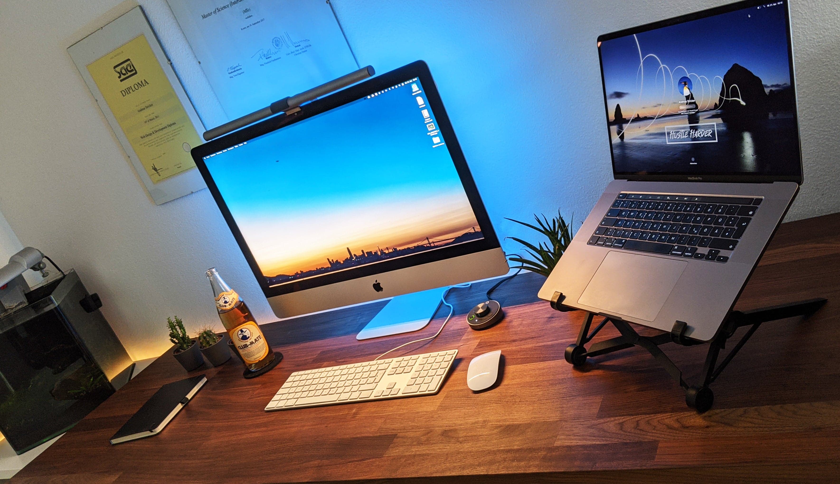 Sebuah meja PC gamer dengan tabung lampu silinder hitam menempel elegan di tepian bingkai atas monitor